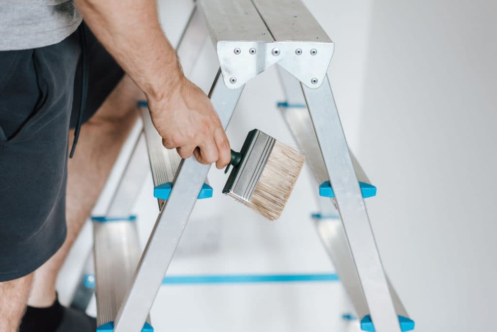 Peintre avec échelle et brosse pendant les travaux de rénovation